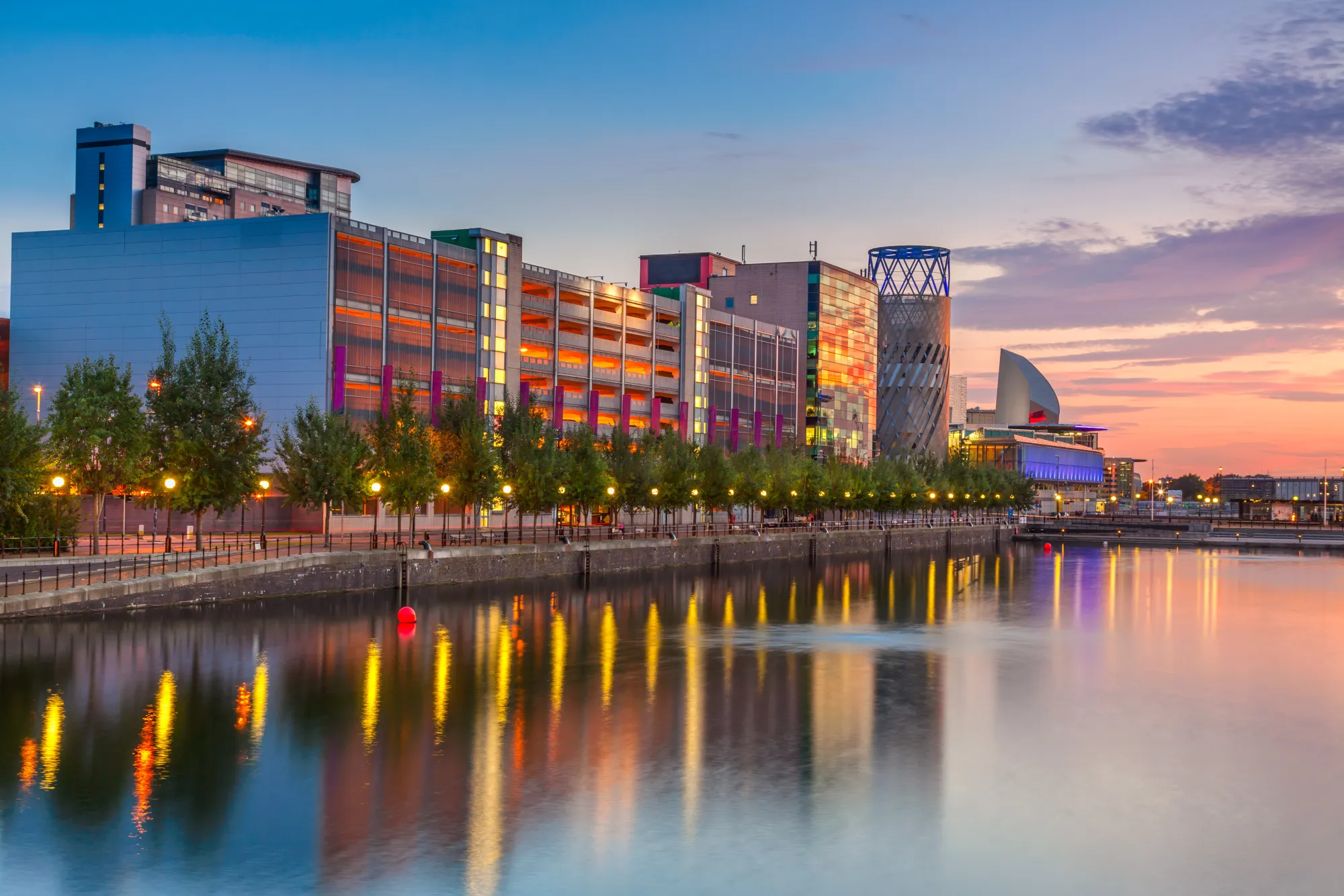 Cityscape of Manchester with modern waterfront buildings and urban skyline along the quays